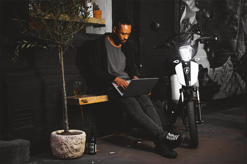 Man sitting down with laptop next to a bike